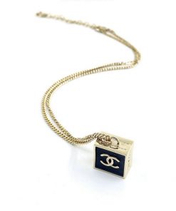 Gold chain necklace with cube pendant.