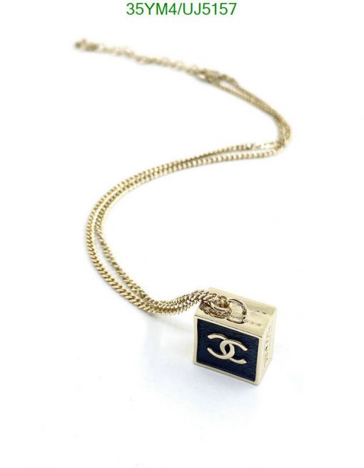 Gold chain necklace with cube pendant.