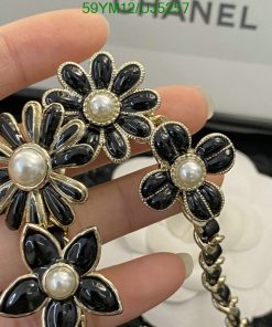 Hand holding black flower pearl earrings.