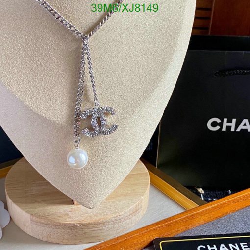 Chanel necklace with logo and pearl on display stand.