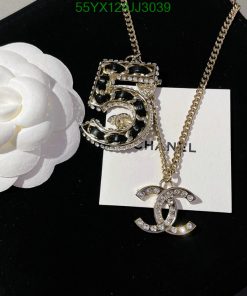 Chanel pendant necklace with flower on black background.