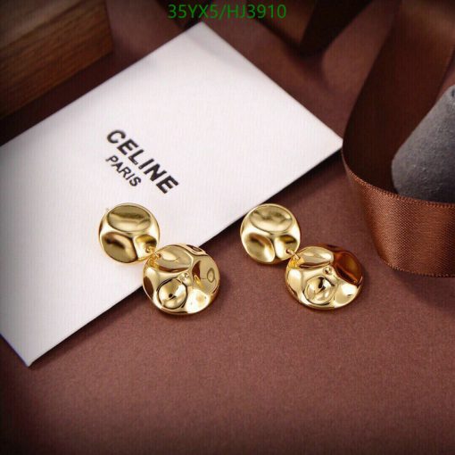 Gold designer cufflinks on brown fabric with packaging.