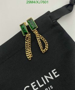 Green gemstone earrings with gold chains on black fabric.