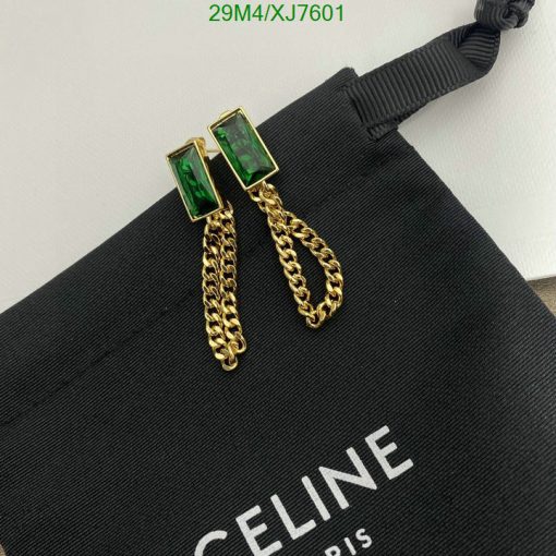 Green gemstone earrings with gold chains on black fabric.