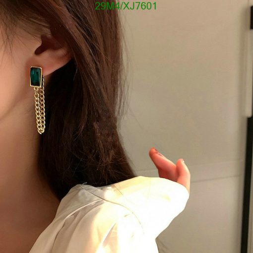 Woman wearing emerald tassel earring.