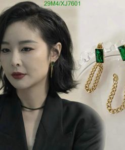 Woman with elegant green earrings and black outfit.