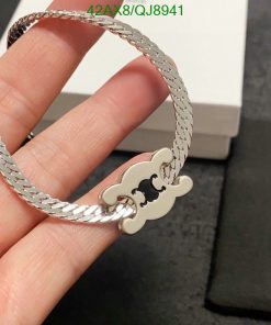 Silver bracelet with designer charm held by a hand.