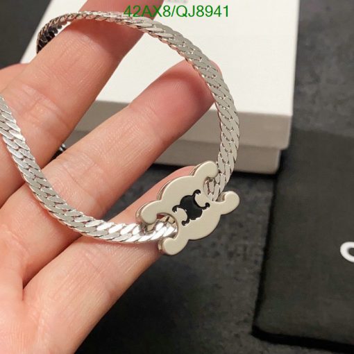 Silver bracelet with designer charm held by a hand.