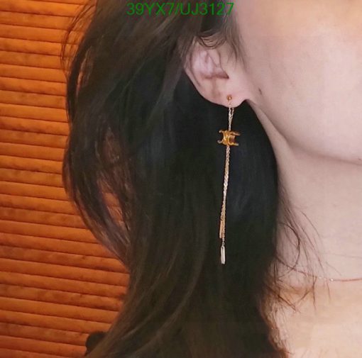 Woman wearing gold dangle anchor earring.