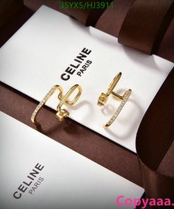 Gold Celine logo earrings on white display with packaging.