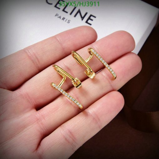 Gold diamond earrings on palm with Celine Paris card.