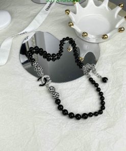 Black beaded necklace with silver accents on white surface.