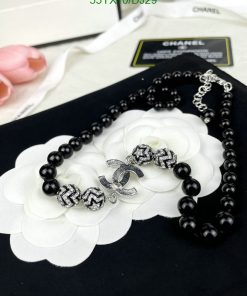 Black bead necklace with white flower and silver charm