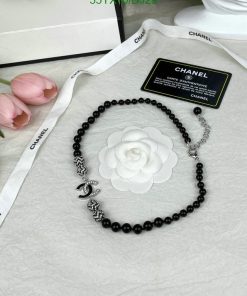 Black beaded necklace with white floral pendant, branding visible.