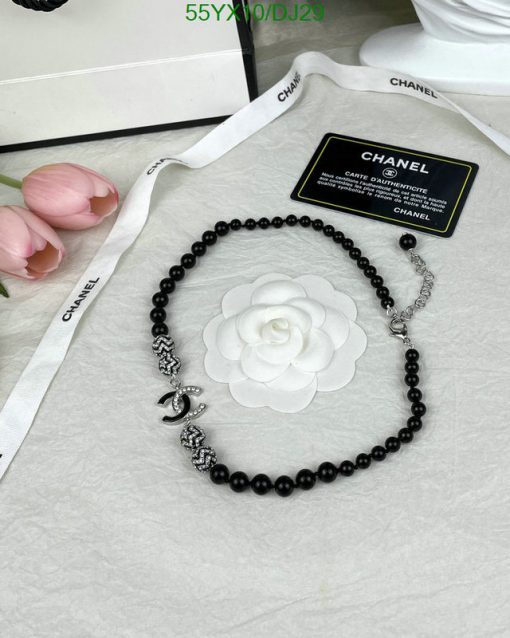 Black beaded necklace with white floral pendant, branding visible.