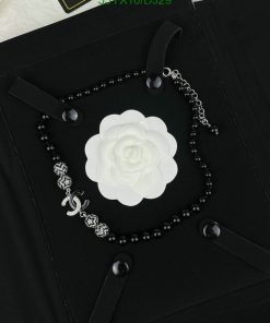 Black bead necklace with white flower pendant.