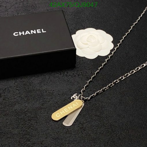 Chanel-branded necklace on black surface with packaging box.