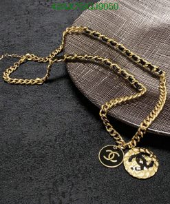 Gold necklace with pendant on textured background.