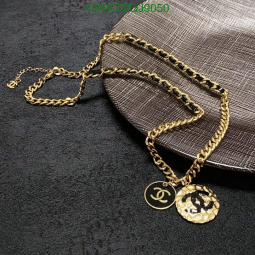 Gold necklace with pendant on textured background.