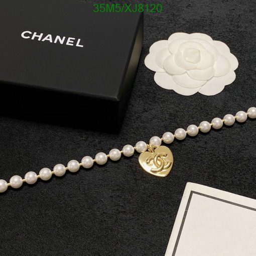 Pearl necklace with gold pendant near luxury brand box.