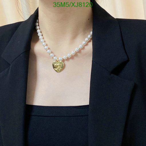 Pearl necklace with gold heart pendant on model.