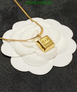 Designer gold pendant necklace on white flower display.