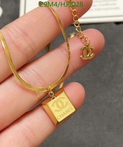 Gold designer logo necklace held in fingers.