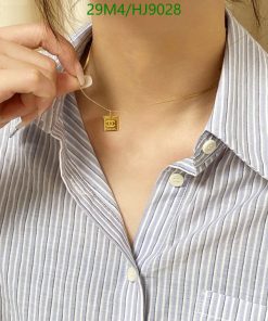 Woman wearing necklace with pendant and striped shirt.