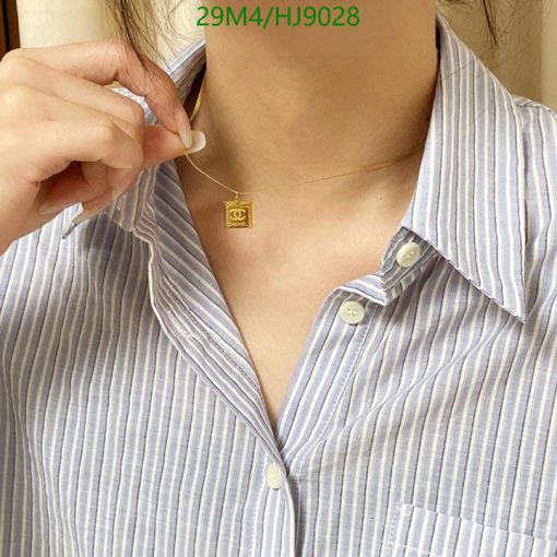 Woman wearing necklace with pendant and striped shirt.