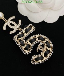 Gold pearl earrings with diamond accents on black surface.