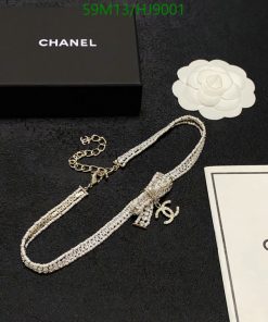 Chanel necklace, box, and camellia flower on black background.