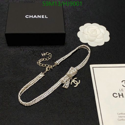 Chanel necklace, box, and camellia flower on black background.