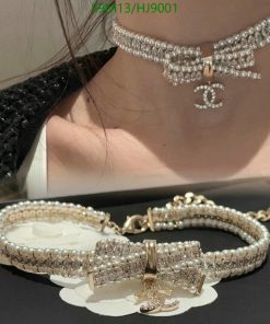 Woman wearing pearl choker and bracelet with logo pendant.