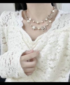 Woman wearing lace top and pearl charm necklace.