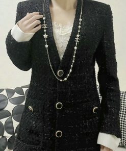 Woman wearing elegant black tweed jacket with pearl necklace.