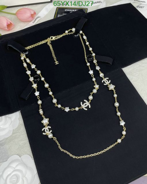 Elegant pearl and star charm gold necklace on black backdrop.