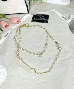 Elegant pearl necklace on textured surface with flowers.