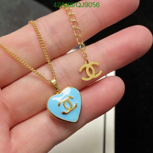 Gold pendant necklace with heart charm held in hand.