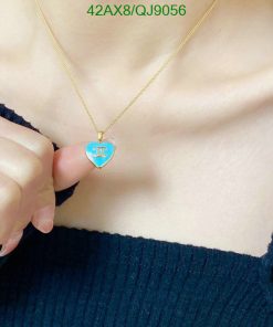 Gold necklace with heart pendant held by person.