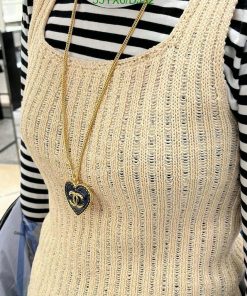 Woman wearing beige knit top and gold necklace.