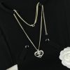 Black shirt with a heart-shaped pendant necklace.