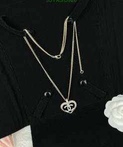 Black shirt with a heart-shaped pendant necklace.