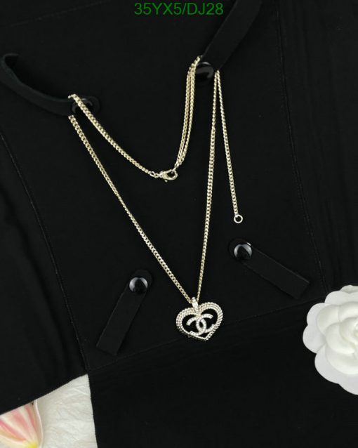 Black shirt with a heart-shaped pendant necklace.