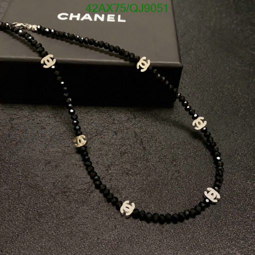 Black beaded designer-style necklace on box.