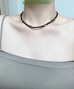 Woman wearing a black beaded choker necklace.