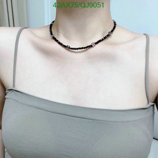 Woman wearing a black beaded choker necklace.