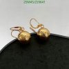 Gold sphere earrings on black surface.