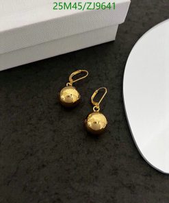 Gold ball drop earrings on dark surface