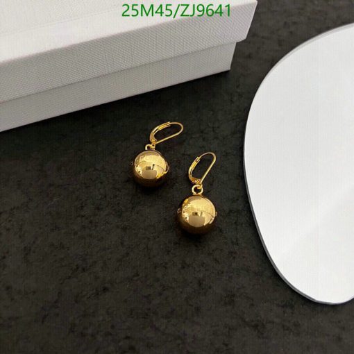 Gold ball drop earrings on dark surface