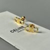 Gold Celine logo earrings on white surface.